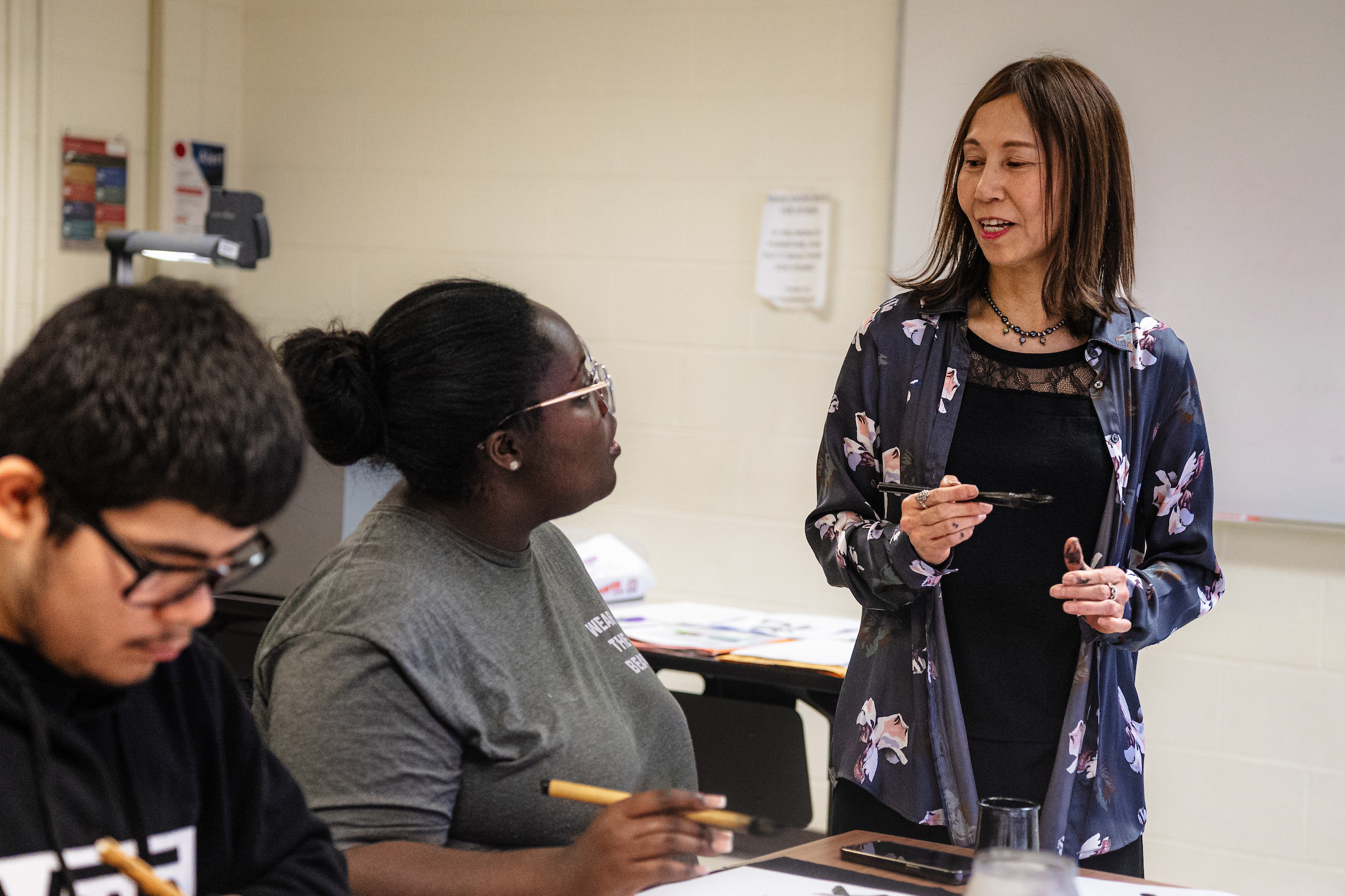 Dr. Minae Yamamoto Savas speaking to a student in her Calligraphy class