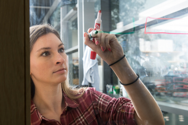 female student mapping with markers on clear glass