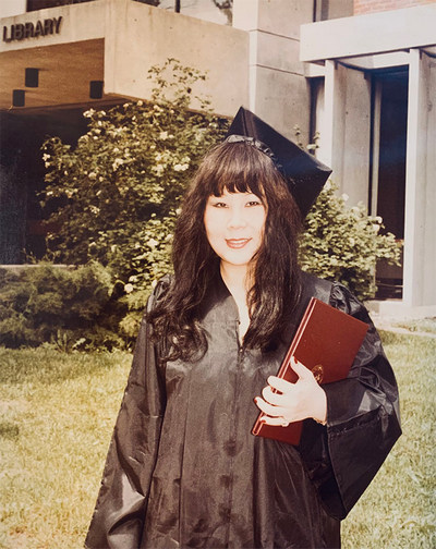 My Lan Tran stands in front of Maxwell Library in her graduation cap and gown.