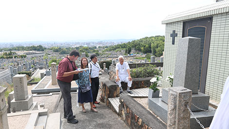 People standing in front of a grave on a hill.