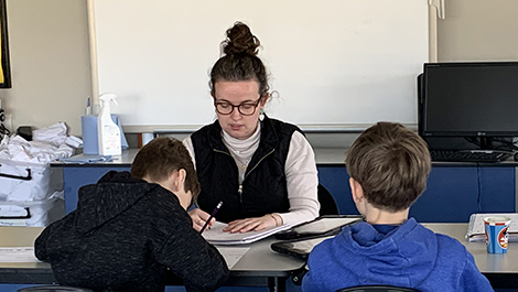 Erin Haley works with two students at a table.