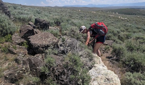 Julia bends over to examine a rock outcrop.