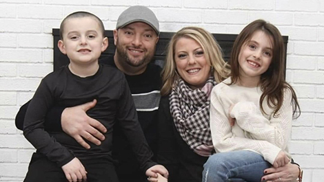 The Gilchrist family poses for a photo in front of a fireplace.