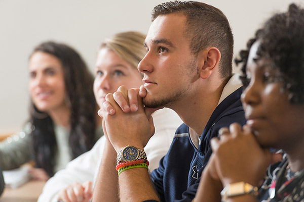 4 BSU students sit at a classroom table in Management class paying positive attention to the professor's lesson