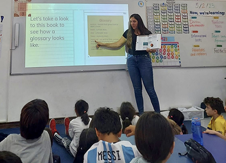 Roslyn holds a book while teaching a lesson about a glossary.