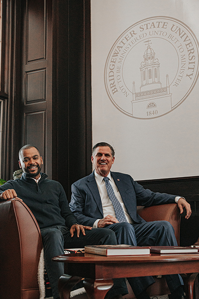 Harold Tavares and President Fred Clark sit in front of a banner with a BSU seal.