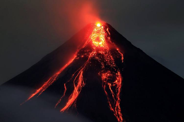 a live volcano with red lava flowing down and red gas billowing from the top