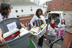 four BSU students unloading baskets of goods from a van with Baskets of Love project