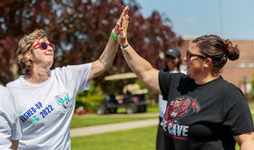Two employees wearing sunglasses and high fiving outside