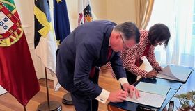 A man and woman are at a desk signing documents