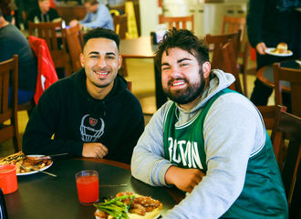 Two students smiling at a table in Flynn Dining Commons