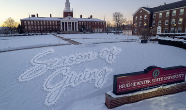 A message that reads &quot;Season of Giving&quot; is seen in the snow in front of a building