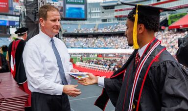 A graduate accepts an envelope with cash from Rob Hale.