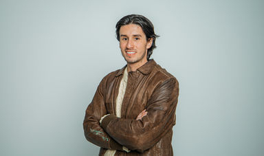 A man stands with his arms crossed and smiles