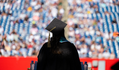 Student stands on commencement stage looking out to the crowd