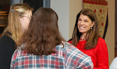 Lucy Croft and two students speak with each other while standing in a hallway.