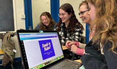 Four students work together on their laptops.