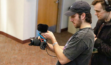 Two students work with a camera in a class about film festival production.