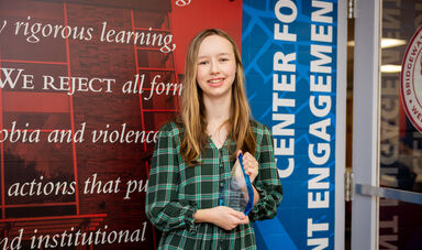A woman with blonde hair holds a glass award in her hands