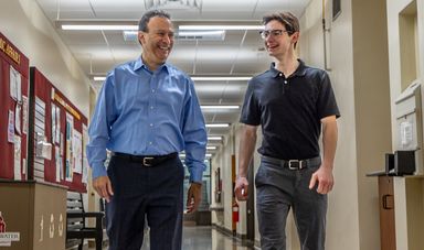 To men walk together in a hall smiling
