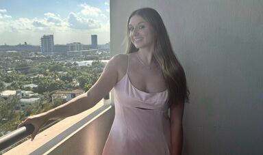 A woman stands smiling on a balcony