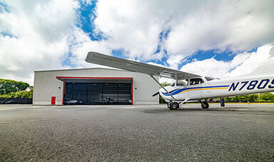 A new hangar with an airplane in the foreground.