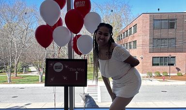 A woman smiles while standing in front of red and white balloons