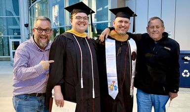 Four men stand smiling