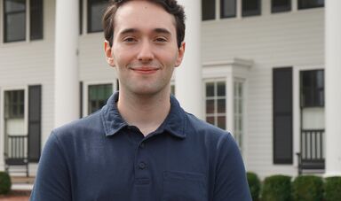A man wearing a blue shirt smiles at the camera