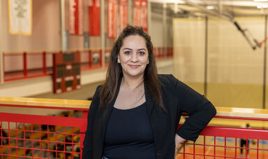 A woman wearing a black shirt stands and smiles at the camera