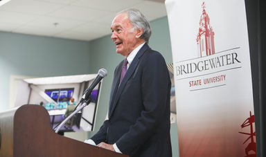 Ed Markey speaks at a podium with the BSU logo on a banner behind him.
