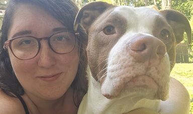A woman wearing glasses poses with her dog