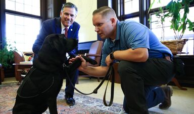 A dog shakes hands with a police officer