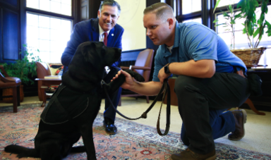 Robert McEvoy shakes hands with Mikey while President Clark looks on