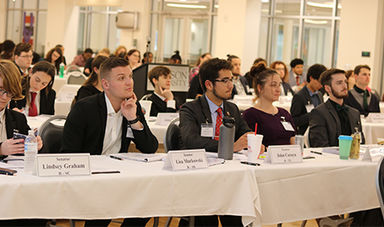 Students portraying senators sit behind tables arranged in rows.