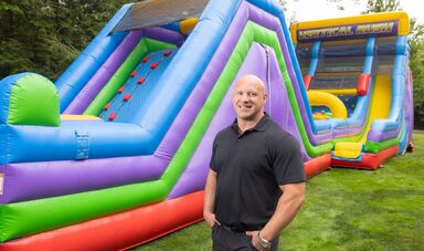 A man stands in front of an inflatable slide