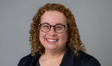 Headshot of Marci Swede in front of a gray background.