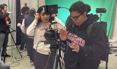 A woman looks down at a camera as she films a scene for a movie