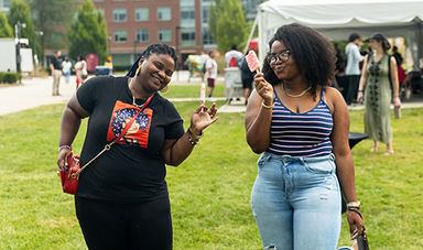 Two students smiling and holding popsicles at the Splash of Color event