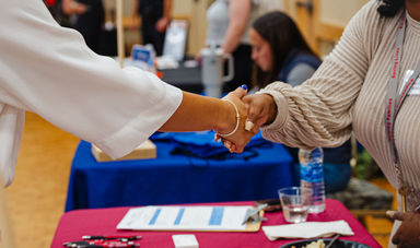 A student shakes hands with a representative at a BSU job fair