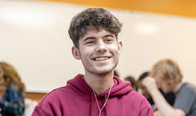 A student smiling in a class for first generation university students