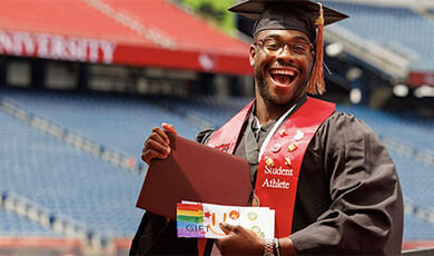 A student holds their diploma and envelope containing money.