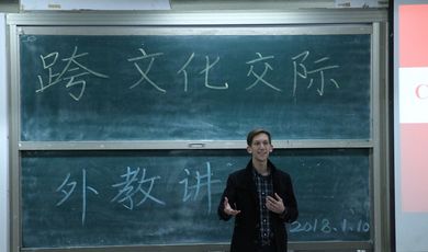 A man stands in front of a chalkboard teaching a class 