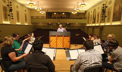 A chorus rehearses on the Horace Mann Auditorium stage.