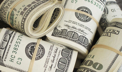 Close-up of five bundles of $100 bills, rolled and secured with rubber bands