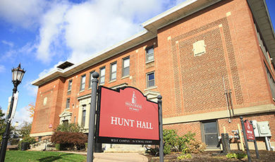 The exterior of Hunt Hall with a red sign identifying the building in the foreground