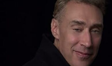 A man wearing a black shirt smiles at the camera 