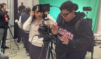 A woman looks down at a camera as she films a scene for a movie 