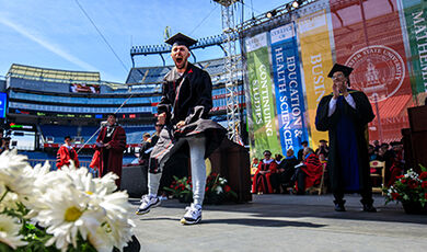 A student shows excitement as he crosses the commencement stage.