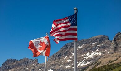 The flags of Canada and the United States with mountains in the background